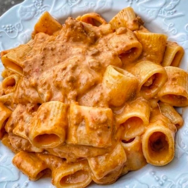 Close-up of Cafe Gia's rigatoni pasta coated in a rich, creamy orange sauce, served in a white bowl.