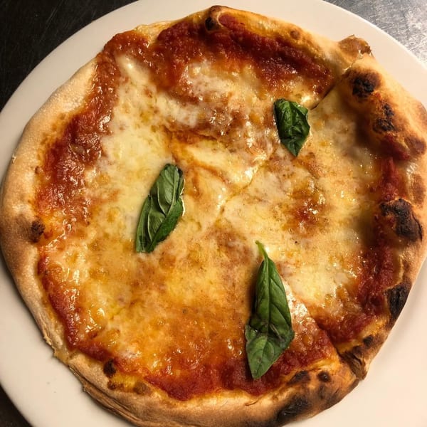 Cafe Gia's Margherita pizza with melted cheese, rich tomato sauce, and fresh basil leaves.